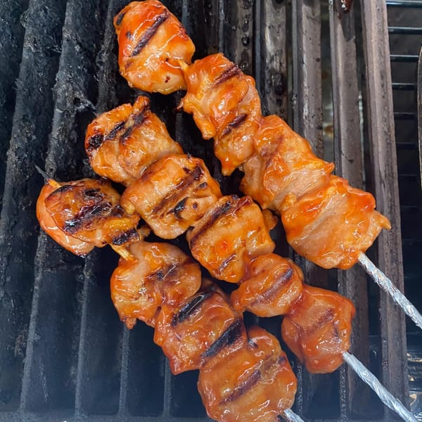 Maui Teriyaki and Sushi's grilled chicken skewers with char marks on a dark grill.